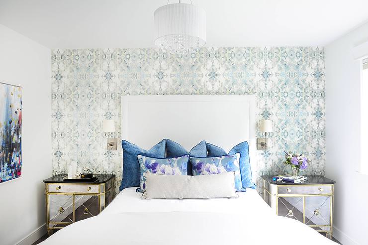 اتاق خواب زیبا با تخت تک نفره سفید و دیوارهای سفید رنگ که دارای دیوار تاکیدی با کاغذ دیواری آبی رنگ می باشد
